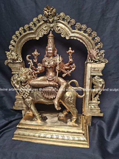 This angle of the Durga idol shows the dynamic posture and the intricate details of the base and archway, all handcrafted in bronze.