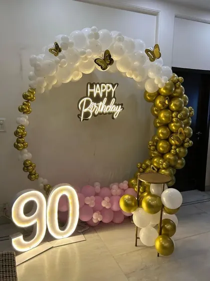Age is just a number, and every number is worth celebrating. I was honored to design this elegant setup for a 90th birthday, featuring a classic white and gold balloon ring, a 'Happy Birthday' neon sign, and large, glowing marquee numbers.