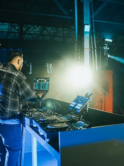 One hand up for the crowd. A dynamic shot from my DJ booth at the Homegrown Festival, with a spotlight catching the moment.