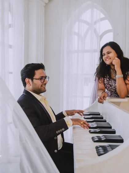 An all-white, classic European-style studio sets the stage for pure romance. The grand piano and crystal chandelier add a touch of musical elegance to this couple's pre-wedding photos.