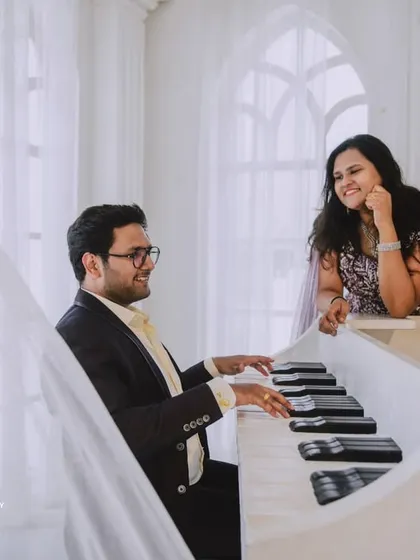 An all-white, classic European-style studio sets the stage for pure romance. The grand piano and crystal chandelier add a touch of musical elegance to this couple's pre-wedding photos.