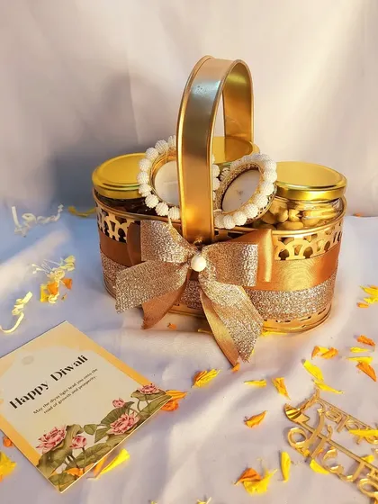 My mini dry fruit basket is a popular choice for return favors or small gestures. This golden metal basket holds two jars of dry fruits and two pearl diyas, tied with a glittering bow.