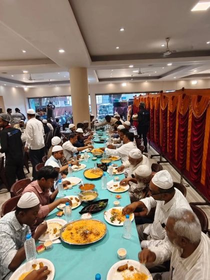 Guests enjoying their meal at a long table, with large platters of biryani served family-style, fostering a sense of community.