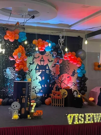 A wider view of the Halloween party stage, showing the full backdrop, balloon arrangement, and personalized marquee letters for the birthday boy.