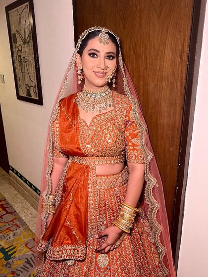 A full-length view of our happy client in the traditional orange bridal lehenga. The outfit offers a beautiful flare, making for stunning pictures.