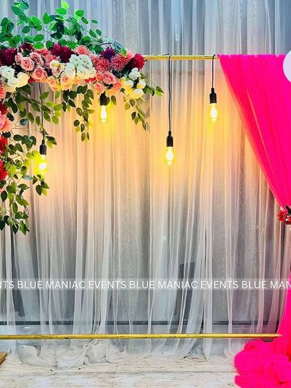 A simple and modern backdrop stand with a floral arrangement and hanging bulbs. This versatile piece can be customized for any event, from birthdays to engagements.