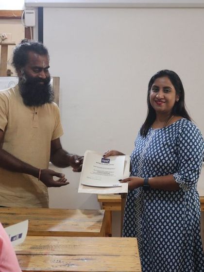 A student is awarded her certification. This moment represents the culmination of months of practice, learning, and creative growth.