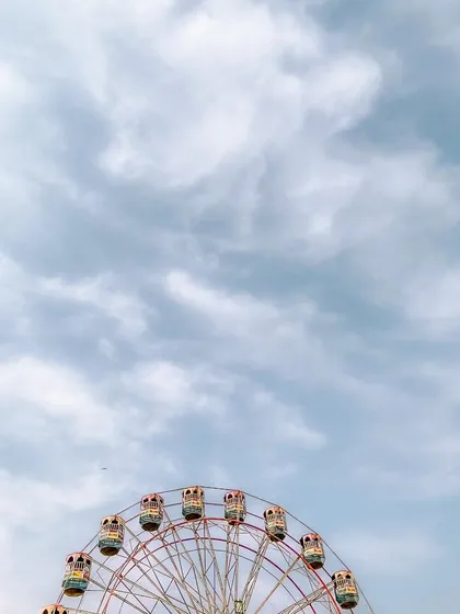 A minimalist shot of the Ferris wheel, positioned at the bottom of the frame under a dramatic sky. This composition plays with scale and perspective for an artistic effect.