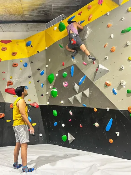 A climber gets some guidance from a spotter on one of our bouldering problems. The community here is all about supporting each other and figuring out the beta together.