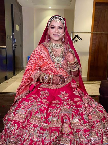 A happy bride on her wedding day, looking absolutely radiant in her traditional red outfit and classic hairstyle.