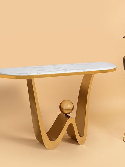 This console table features a playful, modern wave design in its stainless steel base, complete with a balancing sphere accent. The sleek marble top provides a clean surface, making it an eye-catching piece for a hallway or living room.