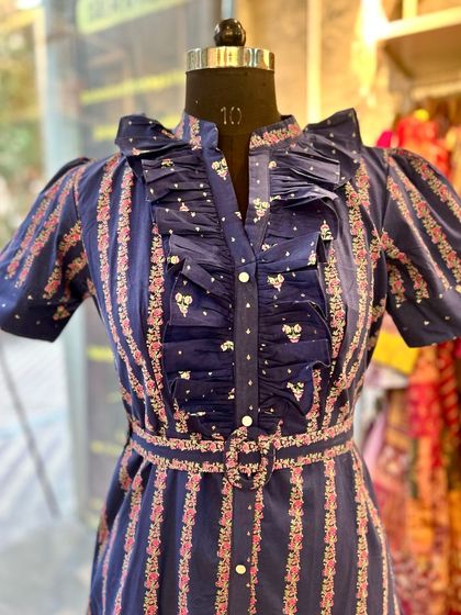 Another look at the beautifully detailed bodice of the retro-style dress. The combination of the ruffled neckline, button-front, and belted waist creates a flattering and unique silhouette.