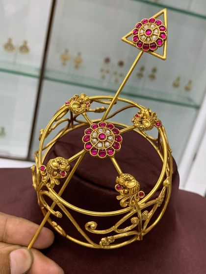 A detailed view of the red stone designer bun cover, highlighting the craftsmanship of the gold-plated frame and the quality of the stones.