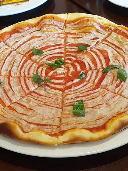 A visually striking pizza with a spiral of tomato sauce and vegan cheese. I work with restaurants to develop unique plant-based pizzas that are both delicious and Instagram-worthy.