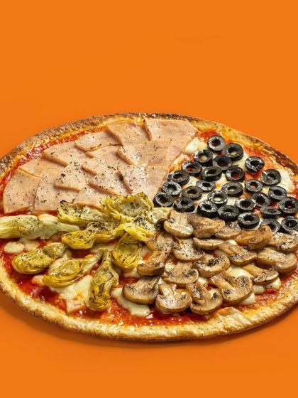 A four-seasons pizza with distinct sections of ham, mushrooms, artichokes, and olives.