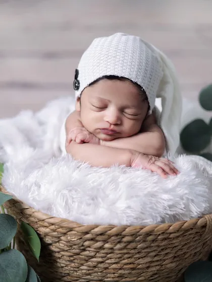 The classic 'chin on hands' pose in a rustic basket. This pose highlights the baby's adorable squishy cheeks and peaceful expression.