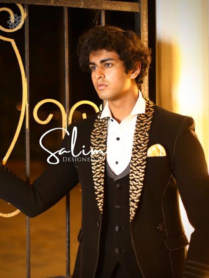 A close-up of the model in the black three-piece suit with a gold patterned waistcoat. The details show the quality of the fabric and the sharpness of the tailoring.