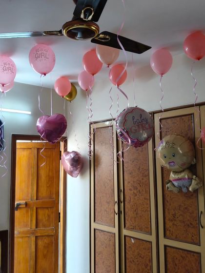 Simple ceiling decorations for a 'Baby Girl' welcome, with pink balloons and themed foil balloons.