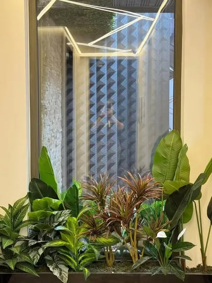 This planter box is filled with a mix of artificial plants, adding color and life below a large window. The composition is carefully balanced to look natural and full from every angle.