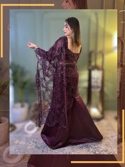 A back view of a stunning wine-colored drape saree gown, highlighting the intricate lacework of the dupatta.