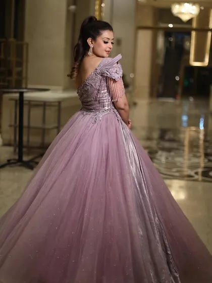 A full-length shot of the royal lavender ball gown, showing its shimmering tulle skirt and unique one-shoulder bodice. The silver metallic panel adds a modern and edgy touch.