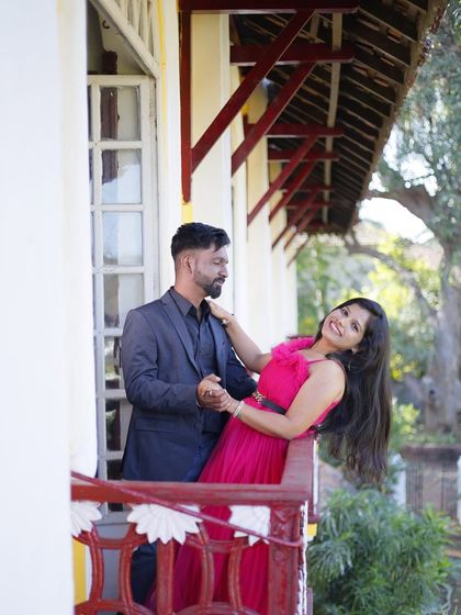 A playful and romantic pre-wedding shot on a balcony. The bright pink gown adds a fun pop of color to this charming photo.
