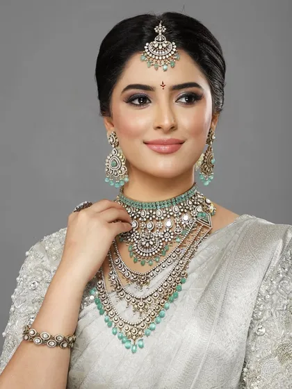 A stunning look in a silver saree with intricate beadwork. The makeup is glamorous, with a focus on defined eyes and glowing skin.