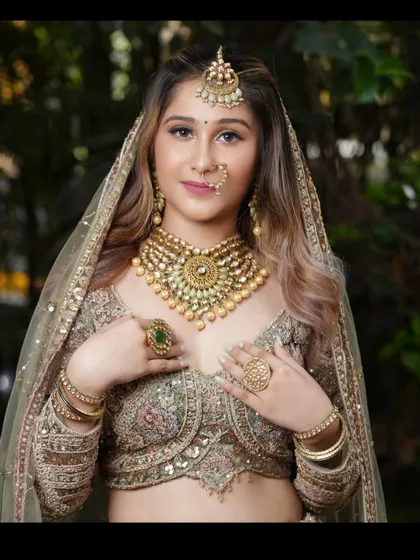A close-up of a bride wearing a heavy gold and mint green jewellery set with one of our pastel lehengas.