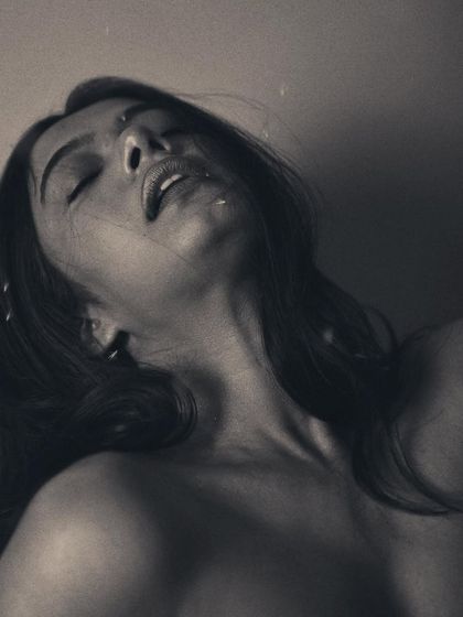 A similar pose with slightly different lighting, this monochrome image feels dreamy and ethereal. The specks of light or dust in the air add to the magical, otherworldly quality of the portrait.