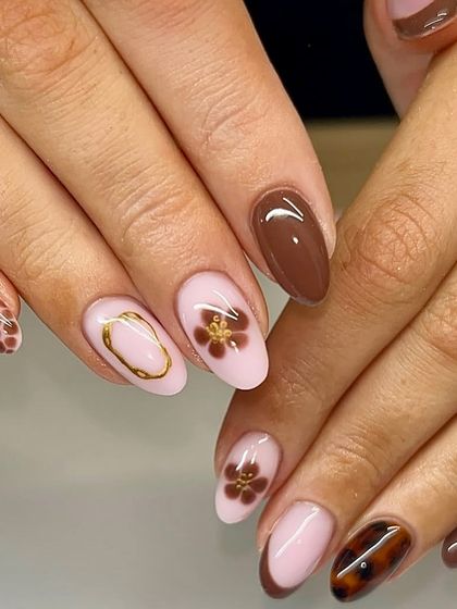 Nails dipped in mocha. This cozy, autumn-inspired set features a mix of brown tones, tortoiseshell print, and delicate floral designs with gold accents.
