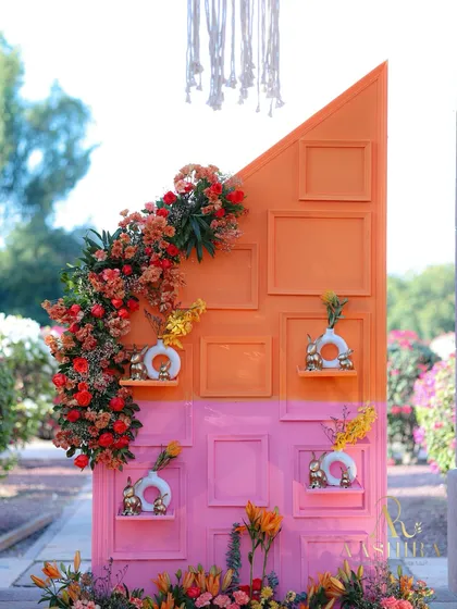 A close-up of the unique photo wall, with its pink and orange panels, empty frames, and shelves holding small decorative vases.
