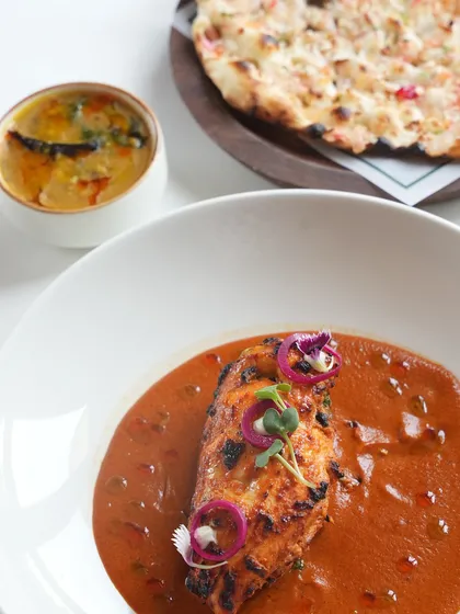 A complete meal featuring our Stuffed Chicken Breast, served alongside our house-made dal and a fluffy, freshly baked naan.