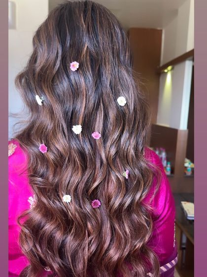 A back view of the soft waves with scattered flowers, a perfect hairstyle for a Mayra or pre-wedding ceremony.