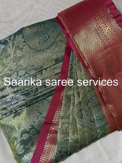 A grey-green saree with a pink border, showcasing a unique color palette.