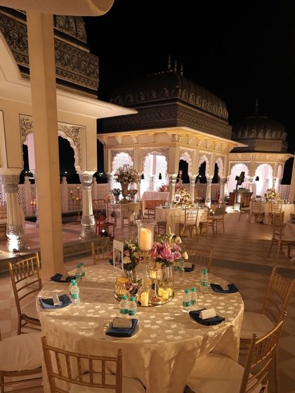 A view of the round table setup for the reception. The combination of high and low floral centerpieces, along with glowing candles, created a dynamic and intimate atmosphere for the guests.