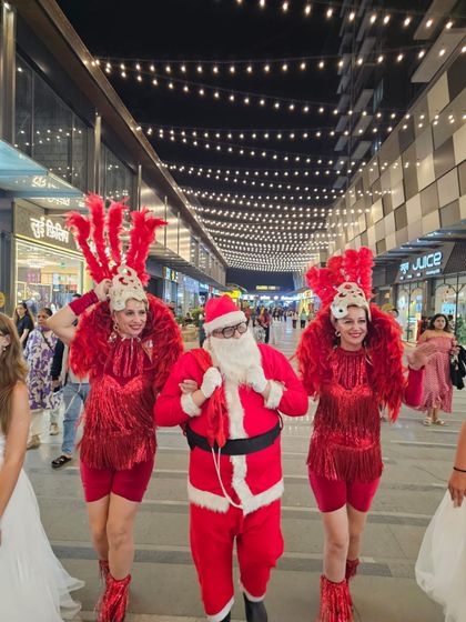 Our Santa Claus accompanied by two vibrant carnival dancers in red feathered costumes. These themed performers are perfect for parades, stage shows, and photo opportunities at any festive event.