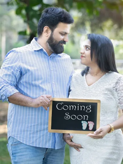 Announcing your greatest adventure. Using simple props like a "Coming Soon" chalkboard is a fun and classic way to share your exciting news during a couple's maternity photoshoot.