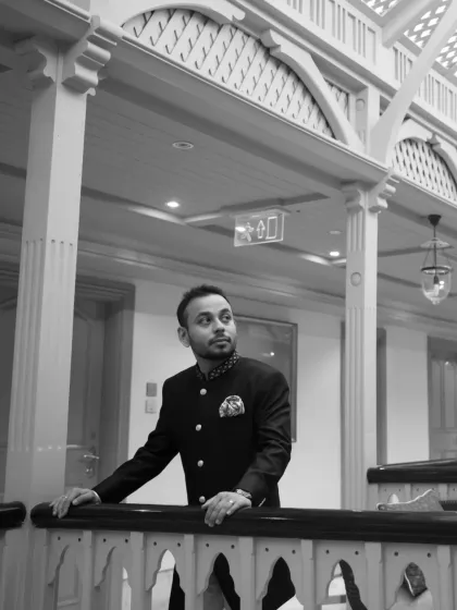 A handsome black and white portrait of the groom, looking thoughtful and elegant in his wedding attire. This shot captures a quiet moment of reflection.