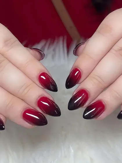 A dramatic red and black ombre on short almond nails, perfect for a bold and edgy look.
