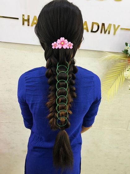 This infinity loop braid is a creative and modern style that students love to learn. It shows how simple accessories like rings and a floral clip can create a unique look.