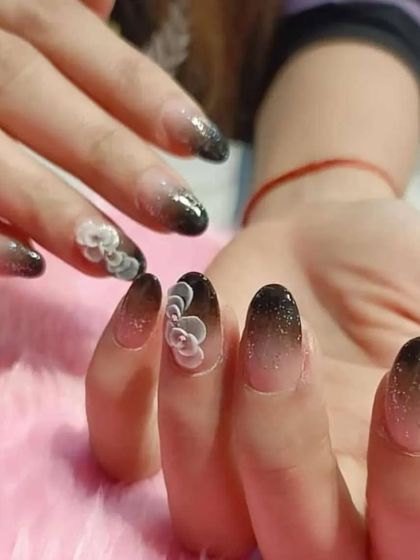 A beautiful black ombre set with a touch of sparkle, elevated by delicate 3D white flowers on the accent nails.