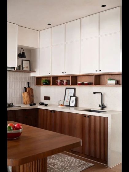 The kitchen combines white upper cabinets with fluted wooden lower cabinets, creating a modern yet warm and textural space.
