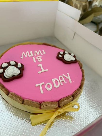 A detailed look at Mimi's custom pink "Pawty Cake" before the celebration. This round cake is perfect for small to medium-sized dogs.