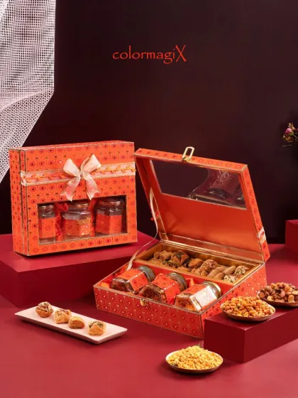 An open view of the orange bandhani print hamper, revealing a rich assortment of sweets and dry fruits. The intricate design and golden accents make it a truly special gift.