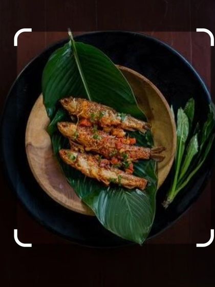 Small fish fried Naga style and served on a banana leaf. This simple preparation highlights the freshness of the fish, seasoned with local herbs and spices.