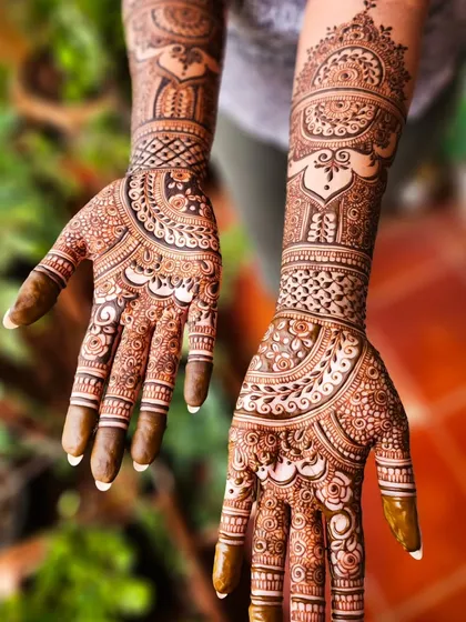 This design combines traditional paisleys with bold, heart-shaped patterns on the palm, extending into detailed arm work.