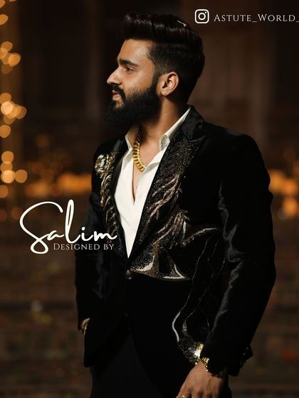 A client in a black velvet blazer with gold and black feather-like embroidery on the lapels. The low lighting highlights the texture and sheen of the garment.
