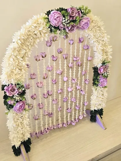 This delicate and charming arch is a lovely choice for a small home Ganpati, featuring a pretty lavender and white color scheme.