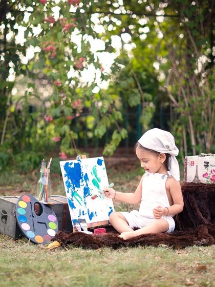 Deep in concentration, this little artist is creating a masterpiece. The lush green background makes the colors of the paint pop.