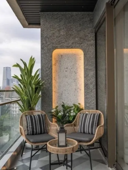 We designed this small balcony as a chic conversation spot with two rattan chairs and a matching table. A textured stone accent wall with integrated backlighting adds a touch of drama and sophistication to the compact space.